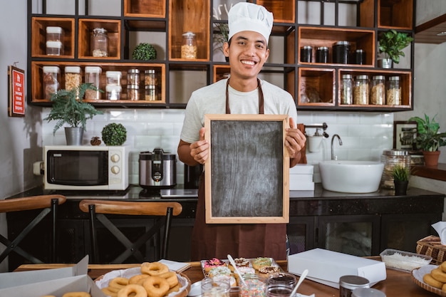 Un atractivo chef masculino sosteniendo una pizarra