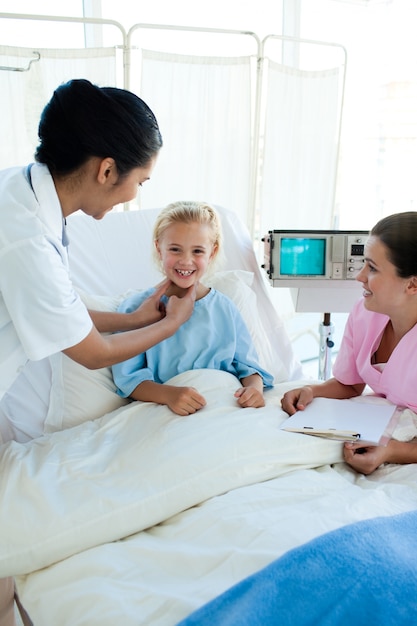 Atractivo doctor examinando a un pequeño paciente femenino