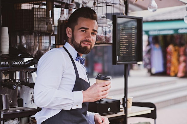 Foto atractivo y elegante barista está tomando café mientras espera a los clientes en su pequeña cafetería.