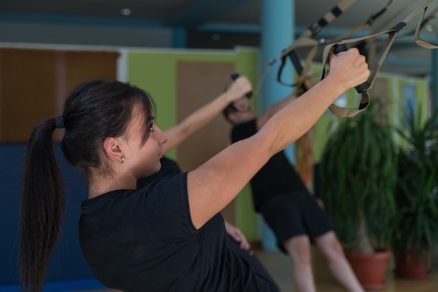 Atractivo entrenamiento en equipo con correas Fitness Trx en el gimnasio