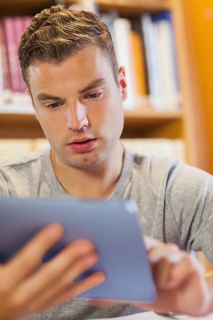 Atractivo estudiante enfocado usando tableta