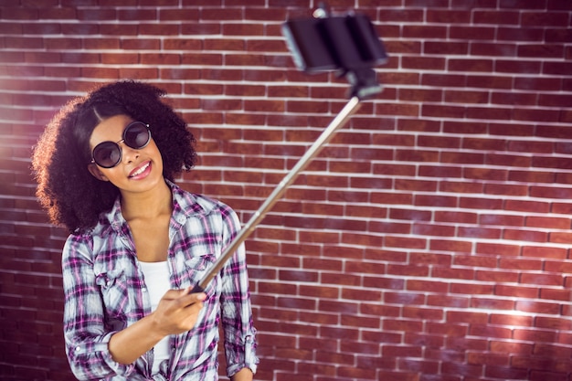 Atractivo hipster tomando autofotos con selfiestick