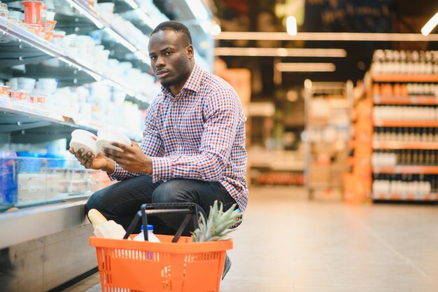 Un atractivo hombre afroamericano haciendo compras en un supermercado.