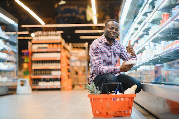 Un atractivo hombre afroamericano haciendo compras en un supermercado.