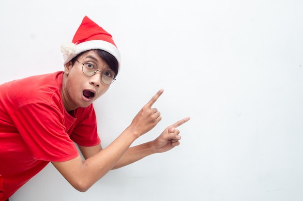 atractivo hombre asiático vestido con ropa navideña roja señalando con el dedo y presentando algo de bienes
