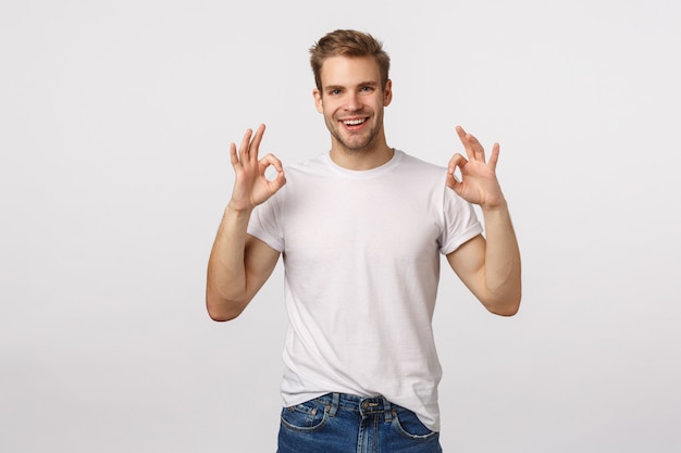 Atractivo hombre barbudo rubio con camiseta blanca dando aprobación