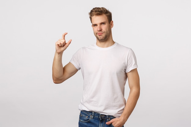 Atractivo hombre barbudo rubio con camiseta blanca haciendo un pequeño gesto