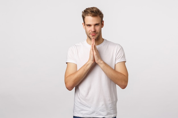 Atractivo hombre barbudo rubio con camiseta blanca rezando