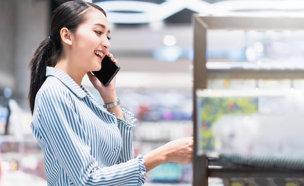 atractivo, inteligente, hermoso, asiático, mujer, bien vestido, comunicación, teléfono inteligente, con, alegre, y, confiado, desenfoque, espacio público, plano de fondo