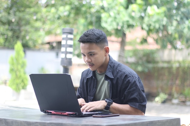 Foto atractivo joven asiático usando laptop en espacio de coworking con cara feliz