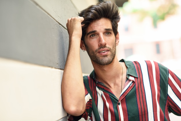 Atractivo joven con cabello oscuro y peinado moderno con ropa casual al aire libre