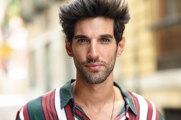 Foto atractivo joven con cabello oscuro y peinado moderno con ropa casual al aire libre