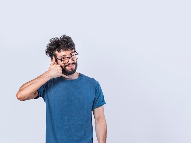 Foto atractivo joven caucásico con ropa informal imita la conversación telefónica mantiene la mano cerca de la oreja como si estuviera sosteniendo un teléfono móvil