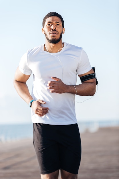 Atractivo joven deportista africano corriendo al aire libre por la mañana