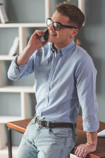 Atractivo joven empresario en anteojos está hablando.