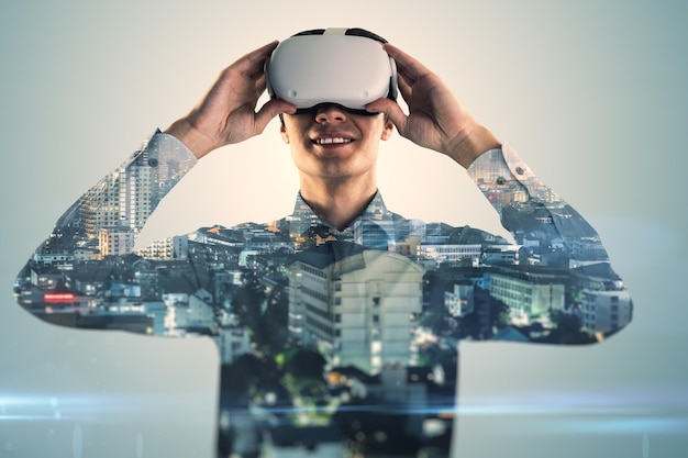 Atractivo joven empresario europeo con gafas de realidad virtual de pie en el fondo borroso de la ciudad Metaverse y concepto de realidad virtual doble exposición