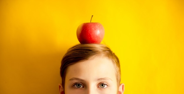 Atractivo muchacho adolescente en la cabeza de manzana en un amarillo