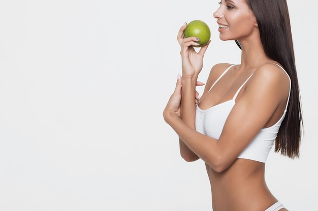 Atractivo retrato de mujer sonriente sobre fondo blanco con manzana