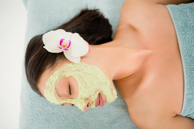 Foto atractivo tener crema verde en su cara en el centro de spa