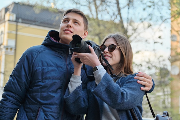 Atractivos turistas masculinos y femeninos tomando fotos con cámara de fotos