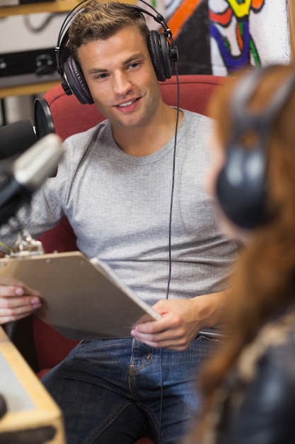 Atraente anfitrião de rádio feliz entrevistando um convidado segurando prancheta