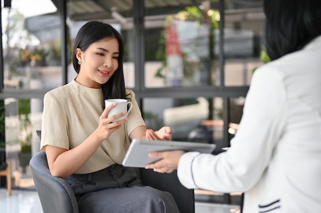 Atraente CEO feminina asiática tendo uma reunião informal com sua secretária no escritório
