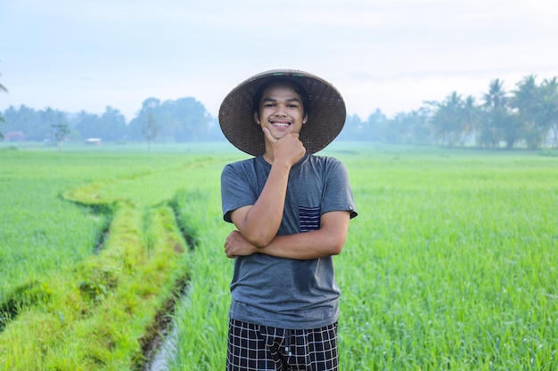 Atraente e alegre jovem agricultor asiático em pé sorrindo e confiante, mostrando sucesso ao crescimento pa