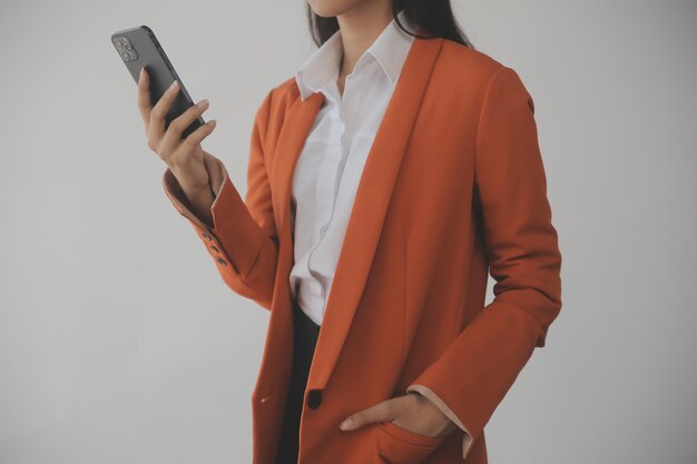 Atraente e sorridente jovem empresária asiática trabalha no escritório em casa Mulher asiática trabalhando em laptop segurando tablet