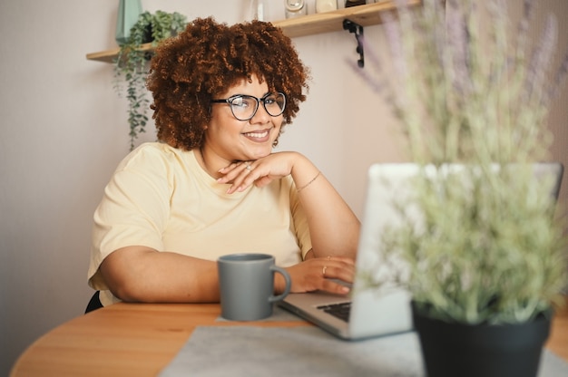 Atraente feliz elegante plus size estudante negra afro-americana de óculos estudando online