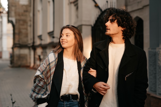 atraente feliz sorridente jovem e elegante casal apaixonado, caminhando e abraçando-se na rua