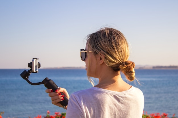 Atraente feminino grava vídeo com moderno 3d gimbal estabilizado smartphone da câmera