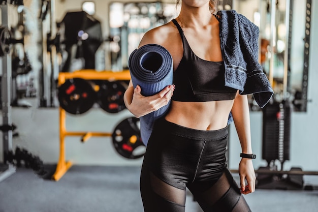 Atraente jovem asiática segura em mãos blues yoga ou esteira de fitness pela manhã no ginásio fitness bodybuilding conceitos de estilo de vida saudável