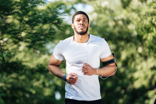 Atraente jovem esportista afro-americano correndo no parque