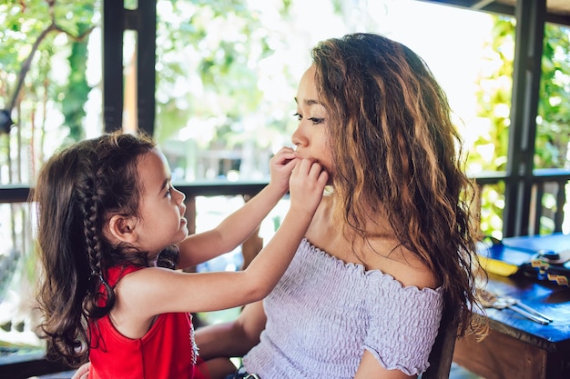 Atraente jovem mãe e adorável filha se divertindo no restaurante