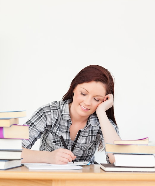 Atraente menina de cabelos vermelhos feliz estudando para um exame