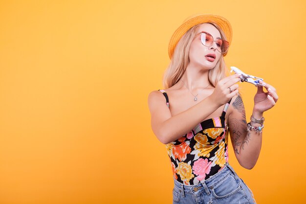 Atraente mulher loira de cabelo playinh com plano de fundo amarelo