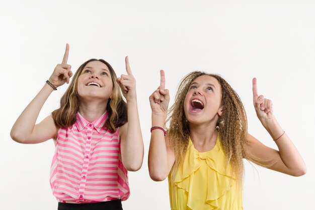 Foto atraente positivo dois adolescente apontando o dedo indicador para cima