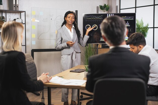 Atraente, sorridente e bem-sucedida jovem empresária mostrando os infográficos de trabalho da empresa