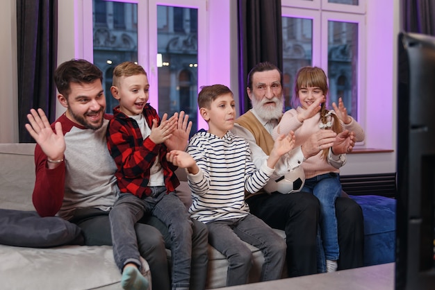 Atraentes três gerações de pessoas como pai, avô e netos que sentados no confortável sofá em casa
