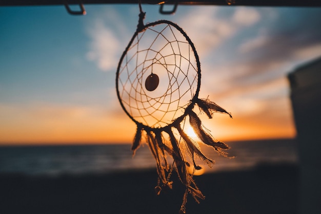 Atrapasueños colgado en la playa con la hermosa vista de la puesta de sol en el fondo