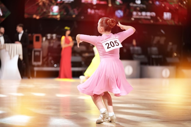 Foto atrás da dançarina, uma dançarina em um vestido rosa pálido contra o fundo do palco.