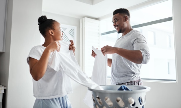 Atrás de cada casa limpa há uma cesta de roupa suja Foto de um jovem casal feliz lavando roupa juntos em casa