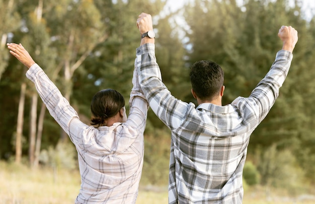 Atrás de caminhadas e casal de mãos dadas para o sucesso na floresta para vitória de conquista ou objetivos de fitness Liberdade de viagem e homem com mulher comemorando jornada de marco e objetivo de aventura na natureza