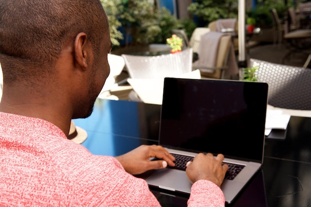 Atrás do homem afro-americano trabalhando no computador portátil