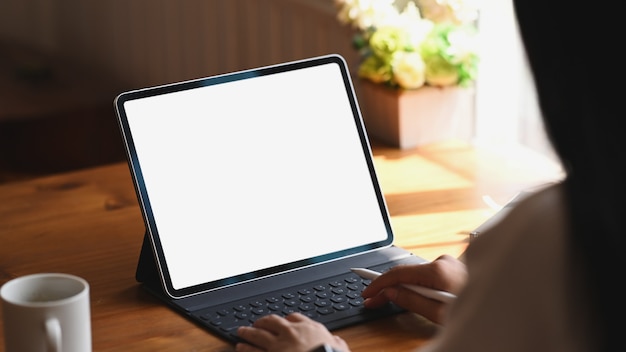 Atrás tiro fêmea digitando seu tablet com tela vazia.