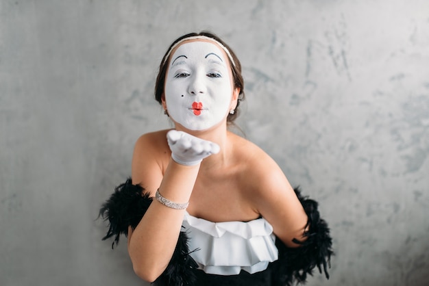 Atriz de teatro pantomima com máscara de maquiagem branca, posando no estúdio. C