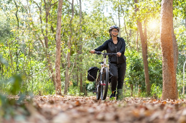 Attraktive ältere asiatische Frau mit Fahrrad im Park