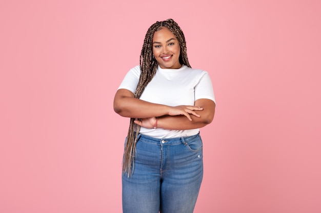 Attraktive afroamerikanische übergewichtige Frau, die über rosa Hintergrund posiert