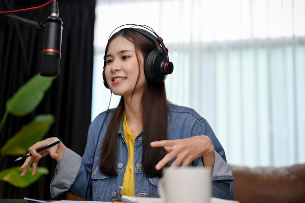 Attraktive asiatische Frau, die ihren Podcast von zu Hause aus aufnimmt und ausstrahlt