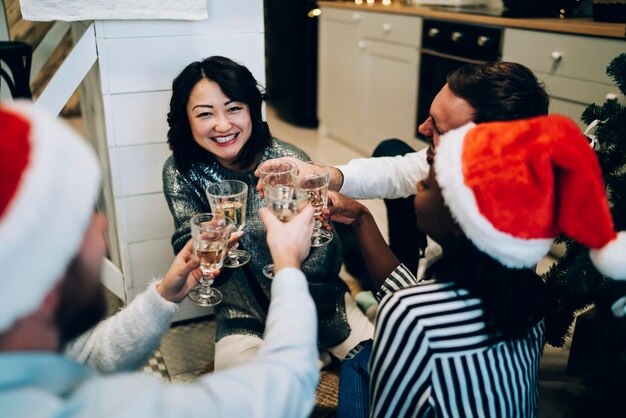 Attraktive asiatische Frau, die mit Freunden auf Weihnachtsfeier klirrt